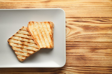 Plate with toasted bread on wooden table