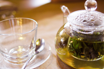 Beverages, good morning and breakfast concept - empty tea cup and teapot with green tea on the table