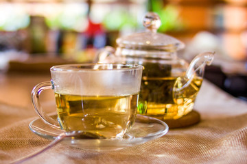 Beverages, good morning and breakfast concept - Cup of white green tea and teapot on the table