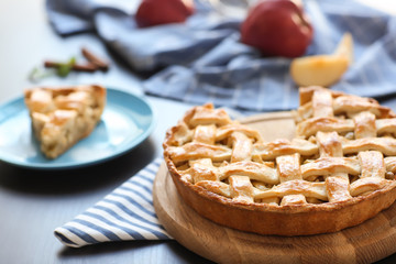 Wooden board with tasty homemade apple pie on table