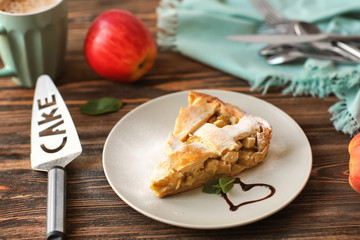 Plate with piece of tasty homemade apple pie on wooden table