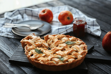 Wooden board with tasty homemade apple pie on table