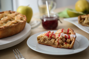 Plate and board with tasty homemade apple pie on table
