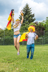Männlicher und weiblicher Fan auf Wiese freuen sich über den Sieg der deutschen Nationalmannschaft