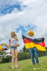 Paar Fussballfan auf Wiese freuen sich über den Sieg der deutschen Nationalmannschaft