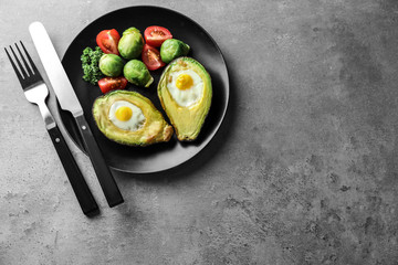 Baked avocado with eggs and vegetables on grey background