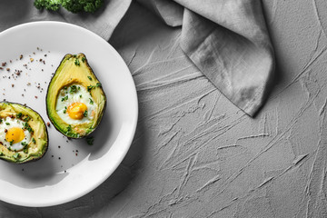 Baked avocado with eggs on grey textured background