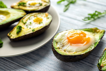 Baked avocados with eggs on wooden table