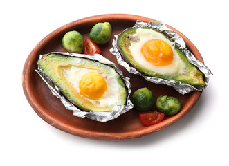 Baked avocado with eggs and vegetables on white background