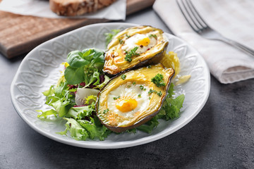 Baked avocado with eggs and vegetables on table