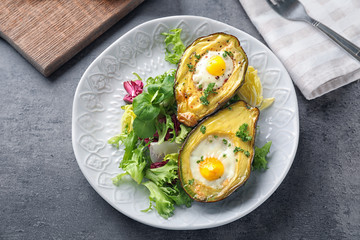 Baked avocado with eggs and vegetables on table