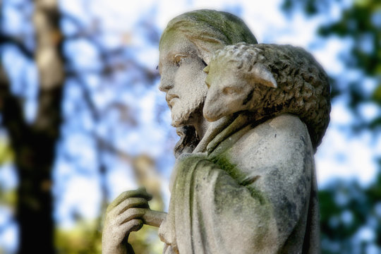 Ancient statue of Jesus Christ is the Good Shepherd with the lost sheep on his shoulders. (Biblical tradition, religion, Christianity, God, faith concept)
