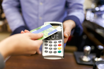 Photo of buyer man with bank card and seller with terminal in hand