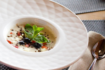 good morning, breakfast and healthy food concept - Tasty oatmeal with strawberries, mint leaves, blueberries and chocolate in white bowl