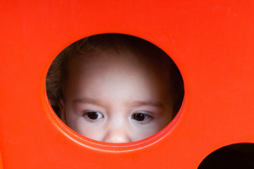 Kind spielt in rotem Kunststoffhaus Baby