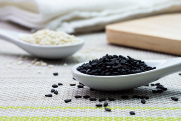 The black sesame on white ceramic spoon with blured white sesame on the back.