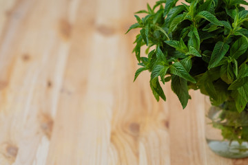 Bunch of fresh mint in glass on wooden background with copy space