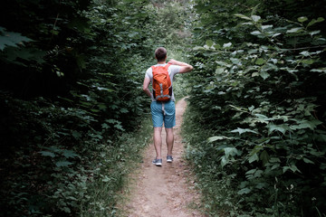 Obraz premium young attractive sporty man walking along a path in the forest