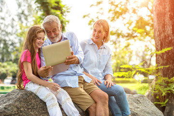 The family is happily sharing a notebook in the garden.Soft focus concept.
