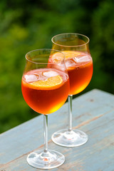 Zwei Gläser mit Spritz Aperol draußen auf einem blauen Holztisch