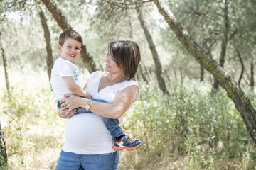 Fototapeta premium Pregnant woman and her son posing in the park