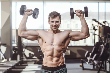 Fototapeta na wymiar handsome strong bodybuilder athletic men pumping up muscles with dumbbells