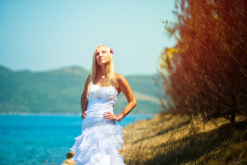 Fototapeta na wymiar Beautiful elegant bride on the sea in nature, beautiful blonde at sunset, enjoying the sun