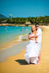 Fototapeta na wymiar the groom embraces the bride on the beach on a hot Sunny day