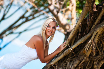 sexy bride posing in the middle of tropical trees against the sea