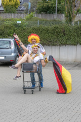 Fußballfans Mann und Frau feiern auf Supermarktparkplatz den Sieg der deutschen Nationalmannschaft