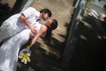 the groom kisses the bride passionately on the stone steps