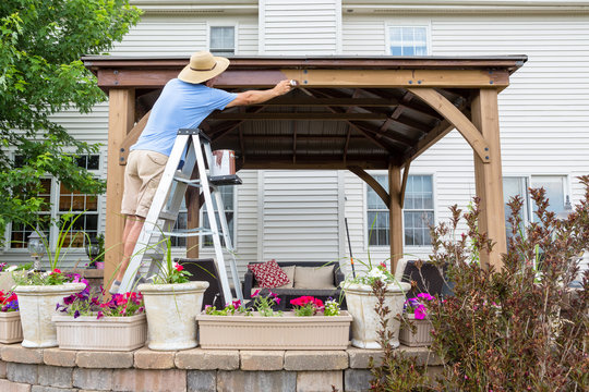 Homeowner Staining A New Gazebo In His Backyard