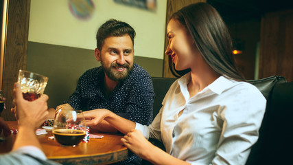 Side view photo of friends sitting at wooden table. Friends having fun while playing board game.