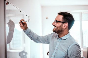 Cheerful man writing on whiteboard.