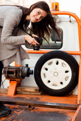 Fototapeta na wymiar Young smiling girl with DSLR camera shooting at old wrecker truck