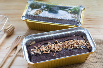 Chocolate cake with almond topping in aluminum foil box packaging.