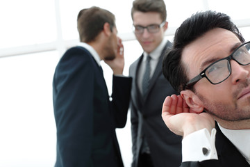 close up.businessman eavesdropping on conversation between colleagues