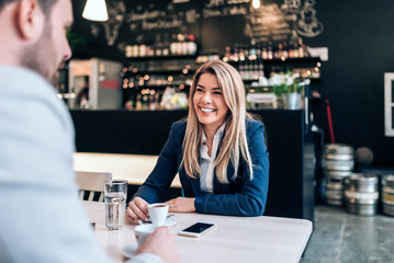 Smiling businesswoman having a cup of coffee with a collegue.