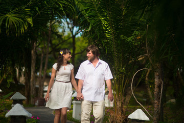 Fototapeta na wymiar happy bride and groom walking in the rainforest, holding hands