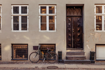 Fototapeta na wymiar parked bicycle with basket near grey building with closed doors on street in copenhagen, denmark