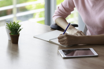 Hand of a woman holding a pencil writing for work.