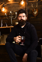 Alcohol addiction. Man with beard holds glass of mulled wine hot seasonal beverage. Guy in cozy warm atmosphere drinking. Man bearded enjoy evening with warming beverage, wooden background