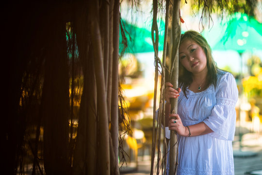 Portrait of a beautiful slightly fat Asian woman posing near tropical branches