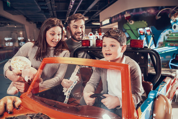 Fototapeta na wymiar Happy family, enraptured son sitting on toy car