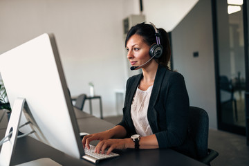 Businesswoman working with headset on computer.