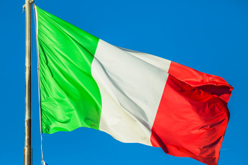 Waving flag of Italy, green white and red colors. waving in the wind on blue sky background.