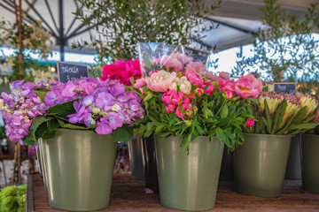 Close up view of buckets with hortensia and peonies on market place