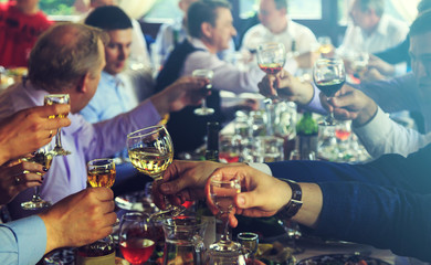 People at the table raise a toast. Close-up glasses