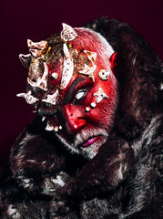 Demon with sharp thorns on head, terror concept. Devil with burning red face isolated on black background. Mysterious creature with white facial hair and dark fur