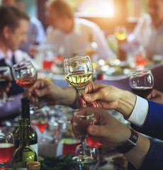 People at the table raise a toast. Close-up glasses